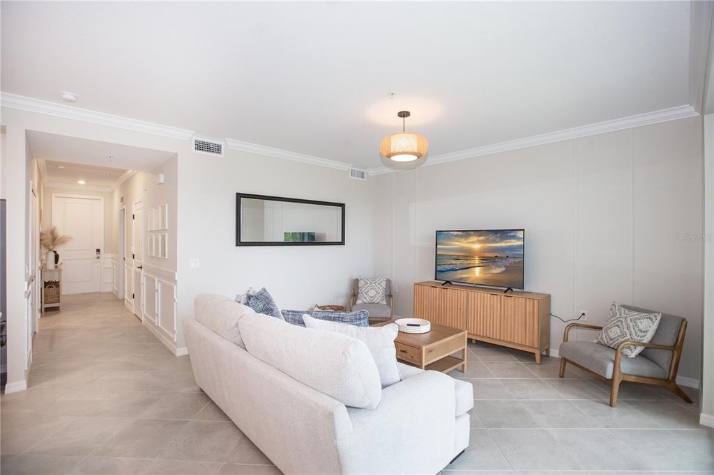 A living room features light tile floors, a white sofa, a television console, and two armchairs — 14141 HERITAGE LANDING BOULEVARD UNIT 922, PUNTA GORDA, FL