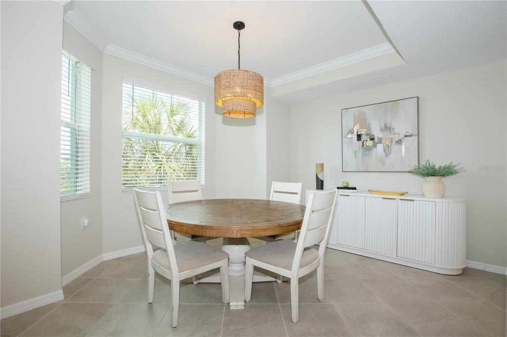 A dining room features a round wooden table, four white chairs, and a woven pendant light — 14141 HERITAGE LANDING BOULEVARD UNIT 922, PUNTA GORDA, FL