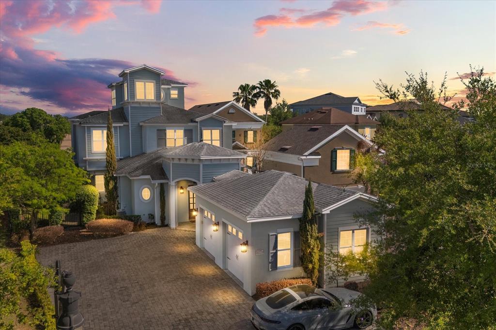 An exterior view of a multi-story blue house with a paved driveway and attached garage — 7447 EXCITEMENT DRIVE, REUNION, FL