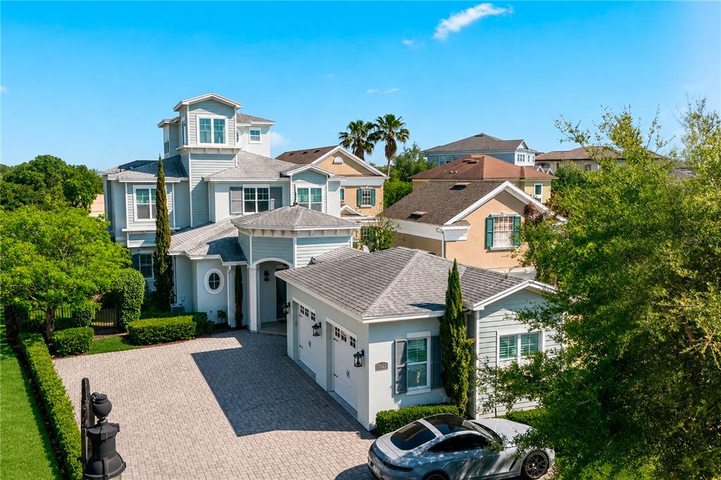A multi-story house with a light blue exterior, a brick driveway, and an attached garage — 7447 EXCITEMENT DRIVE, REUNION, FL