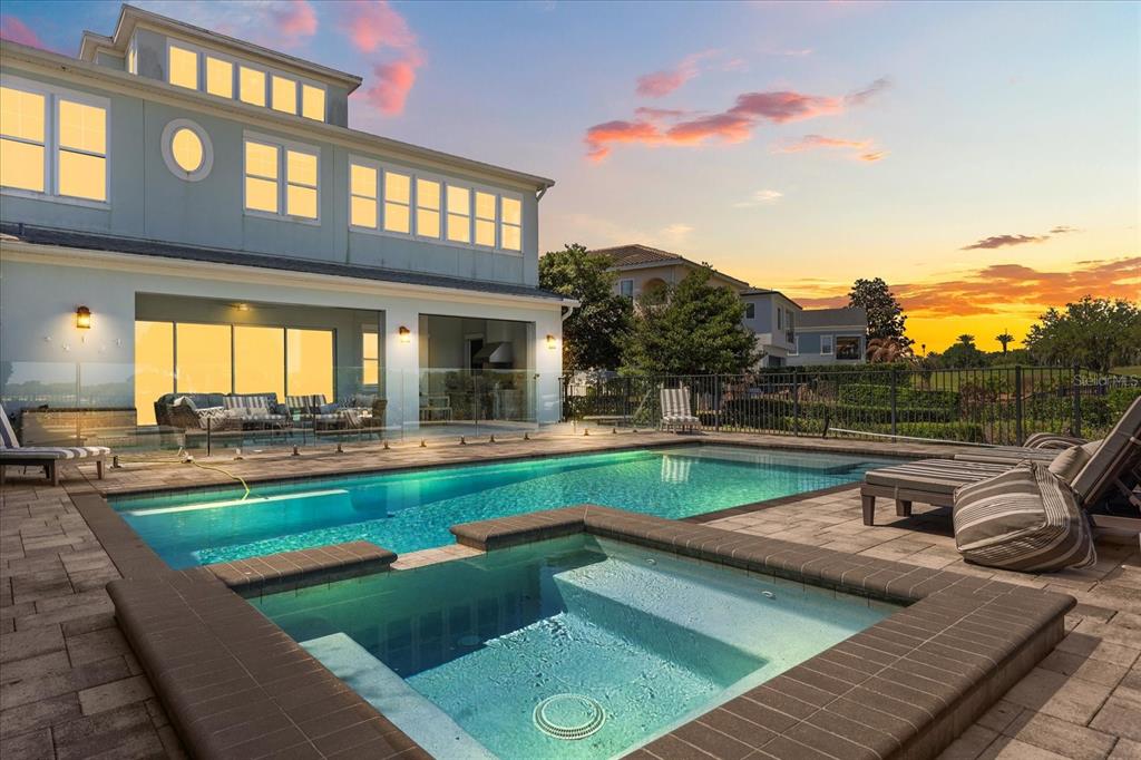 A backyard features a swimming pool and spa with a patio overlooking a sunset view — 7447 EXCITEMENT DRIVE, REUNION, FL