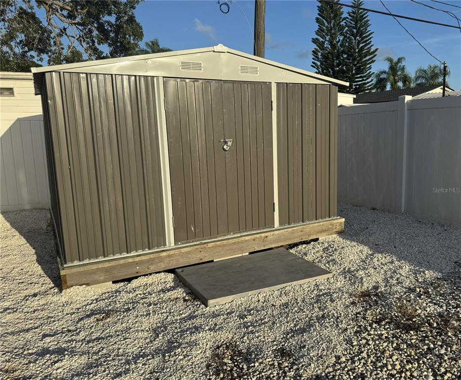 A metal storage shed sits on a wooden base in a gravel yard — 2013 KEPNER DRIVE, HOLIDAY, FL