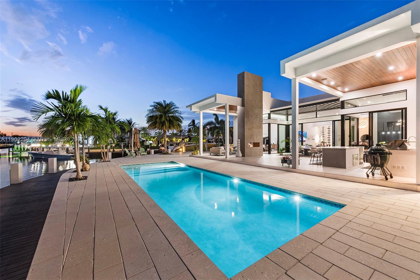 A modern waterfront home features a rectangular swimming pool, a covered patio, and palm trees — 3701 NE 26th Ave # 1, Lighthouse Point FL 33064, LIGHTHOUSE POINT, FL