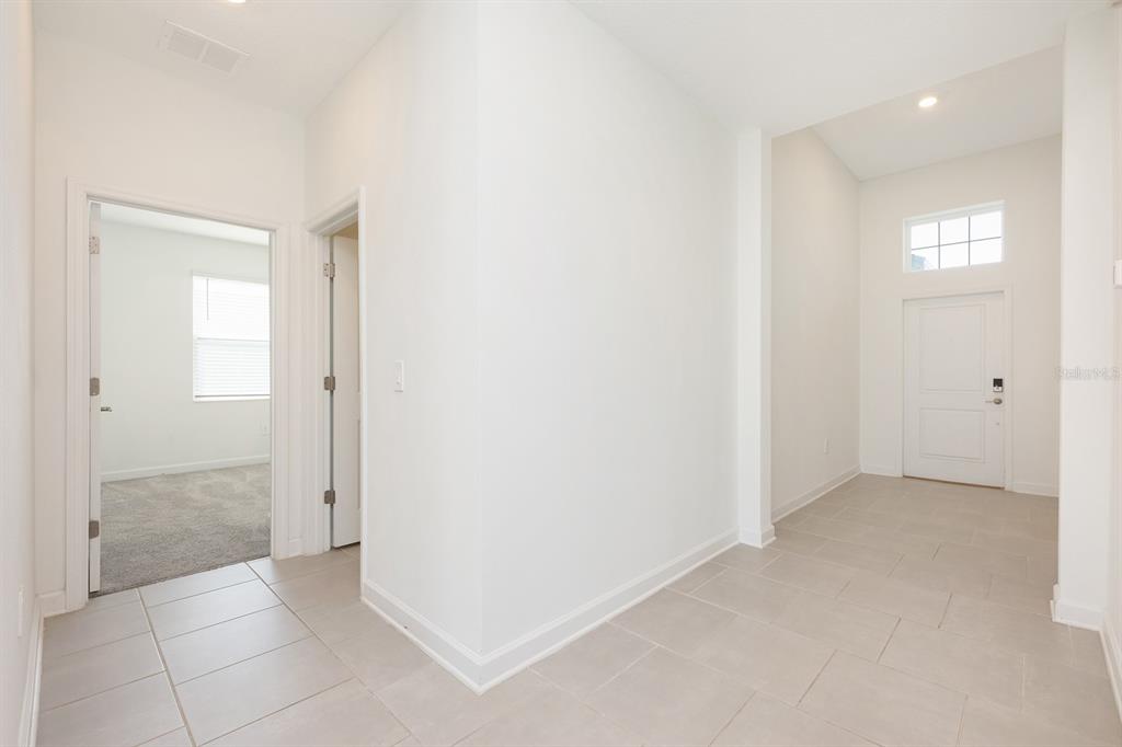 An entryway with light tile flooring leads to a front door and two interior rooms — 3135 CAMDEN WAY, DAVENPORT, FL