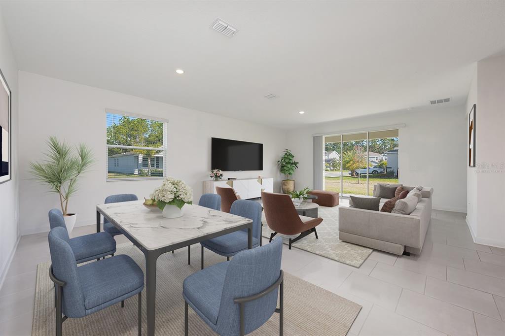 A bright, open-concept living and dining area features blue chairs, a marble table, and tile flooring — 3135 CAMDEN WAY, DAVENPORT, FL