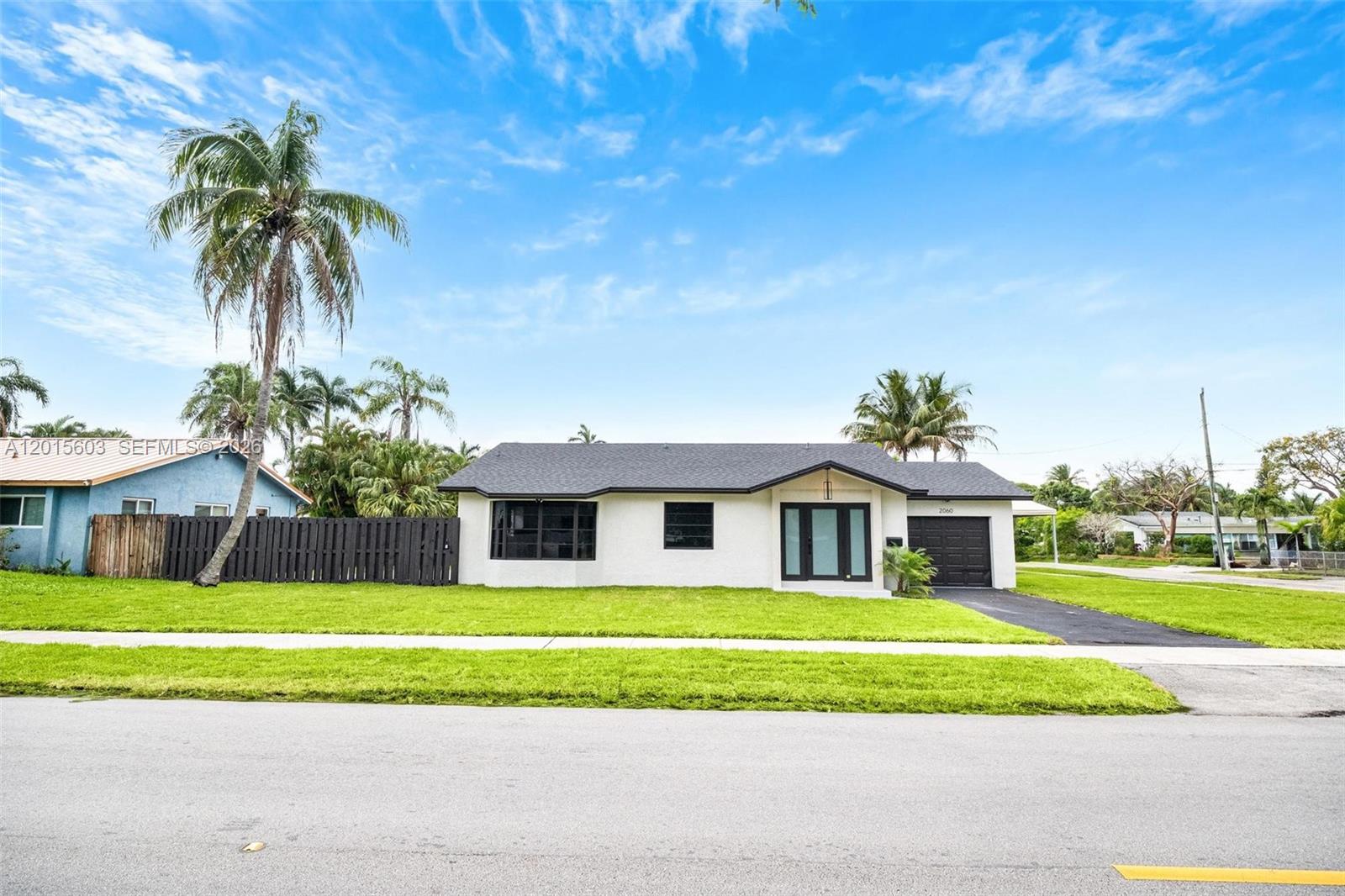A single-story white house with a dark roof and black trim sits on a lawn — 2060 N 26th Ave, Hollywood FL 33020, HOLLYWOOD, FL