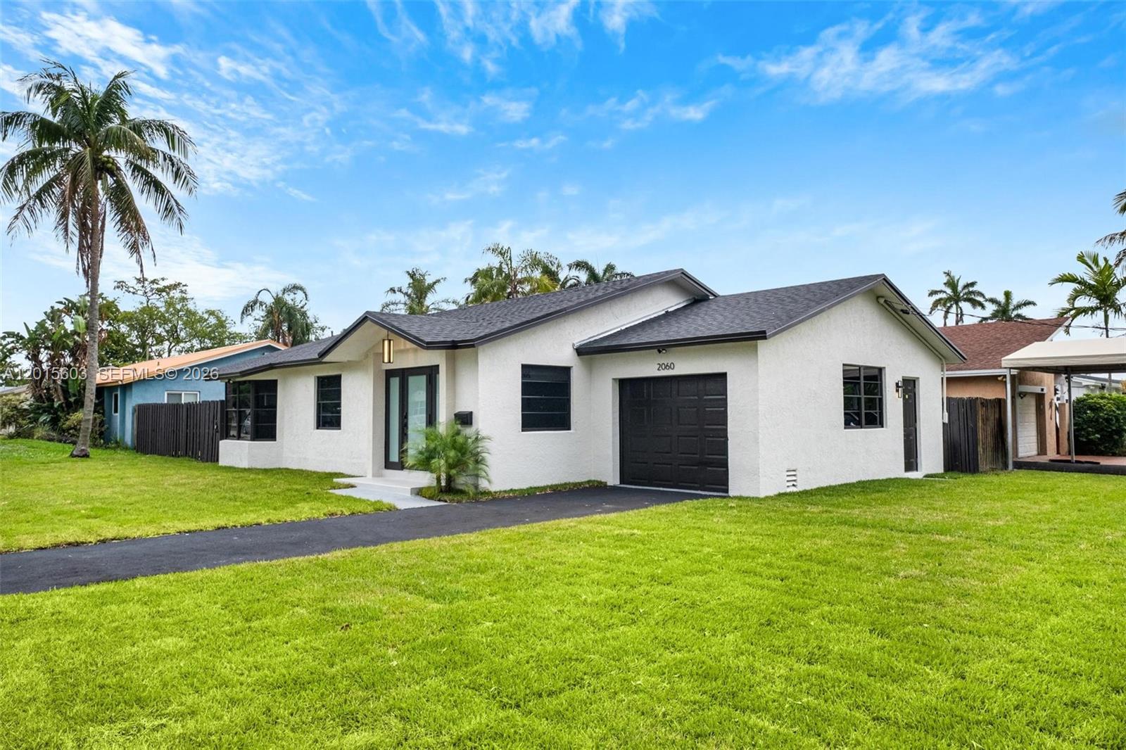 A single-story white house with a black garage door and roof sits on a lawn — 2060 N 26th Ave, Hollywood FL 33020, HOLLYWOOD, FL