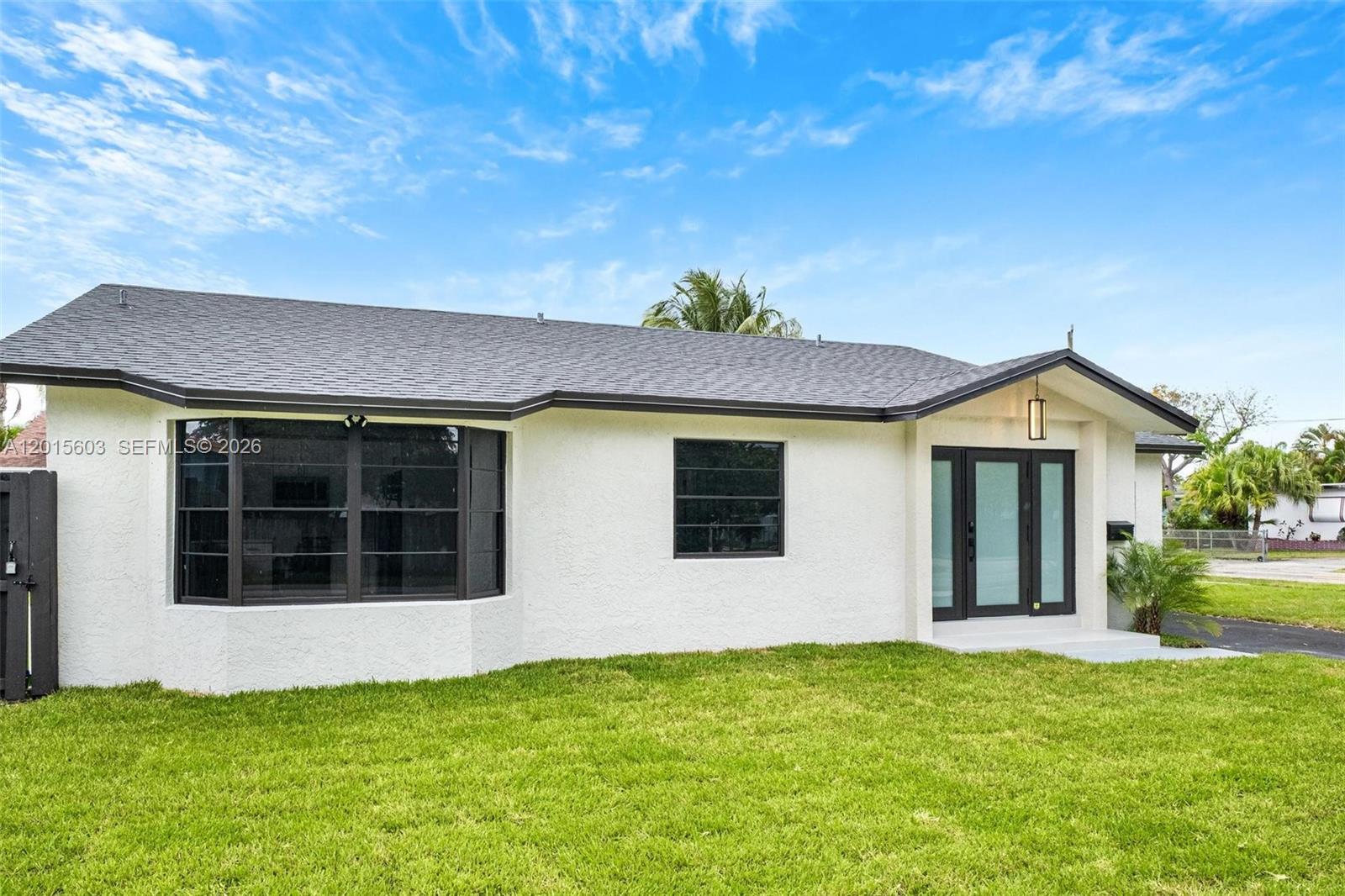 The exterior of a white, single-story house features a dark roof and a bay window — 2060 N 26th Ave, Hollywood FL 33020, HOLLYWOOD, FL