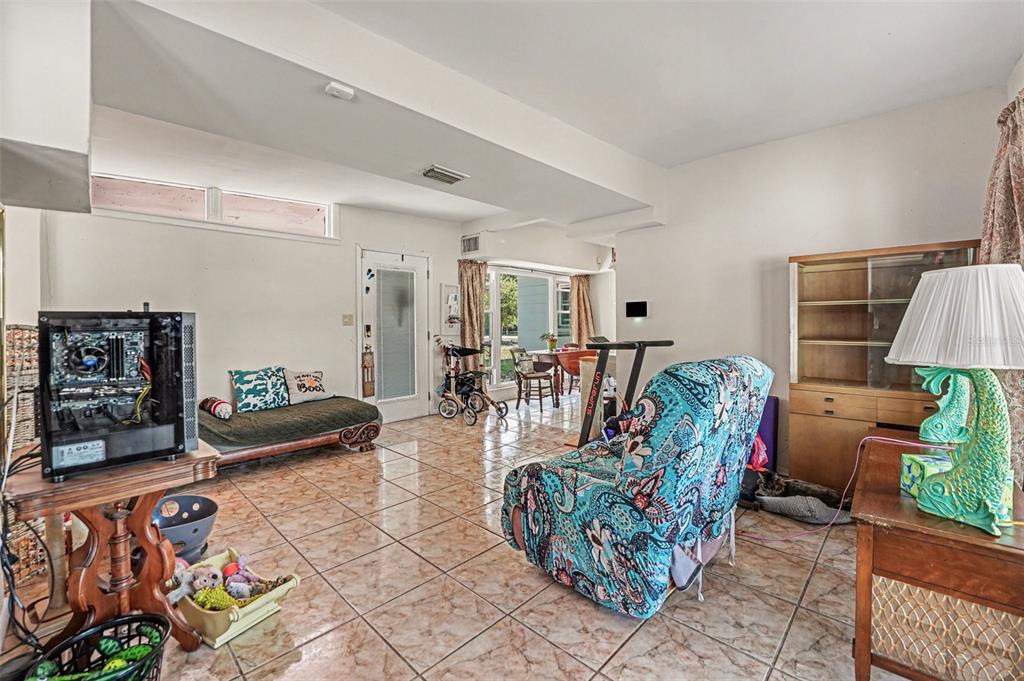 A living room features tiled floors, a patterned armchair, a computer tower, and a doorway — 1431 HESTER DRIVE, LAKELAND, FL