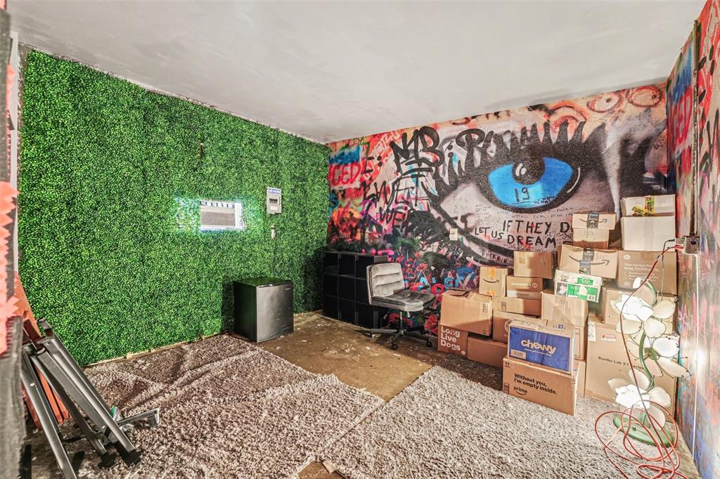A room features a green artificial grass wall, a graffiti-covered wall, and stacked cardboard boxes — 1431 HESTER DRIVE, LAKELAND, FL