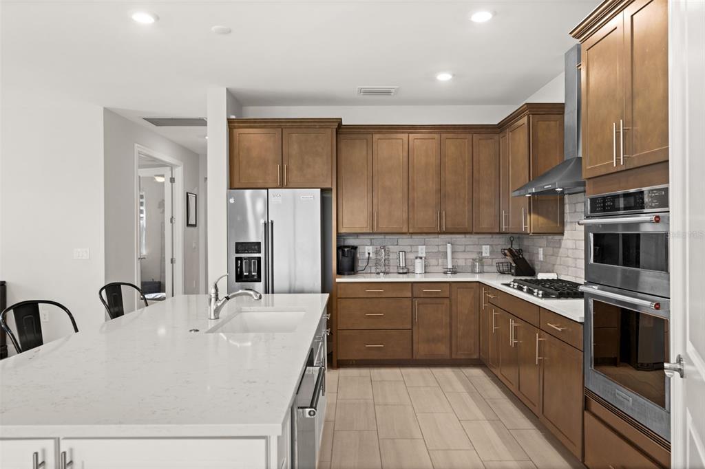 A kitchen features wood cabinets, stainless steel appliances, a white island, and light tile flooring — 42364 EDGEWATER DRIVE, PUNTA GORDA, FL