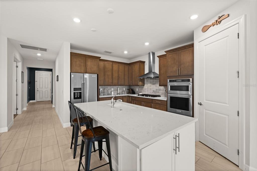 A kitchen features a white island, dark wood cabinets, stainless steel appliances, and tile flooring — 42364 EDGEWATER DRIVE, PUNTA GORDA, FL