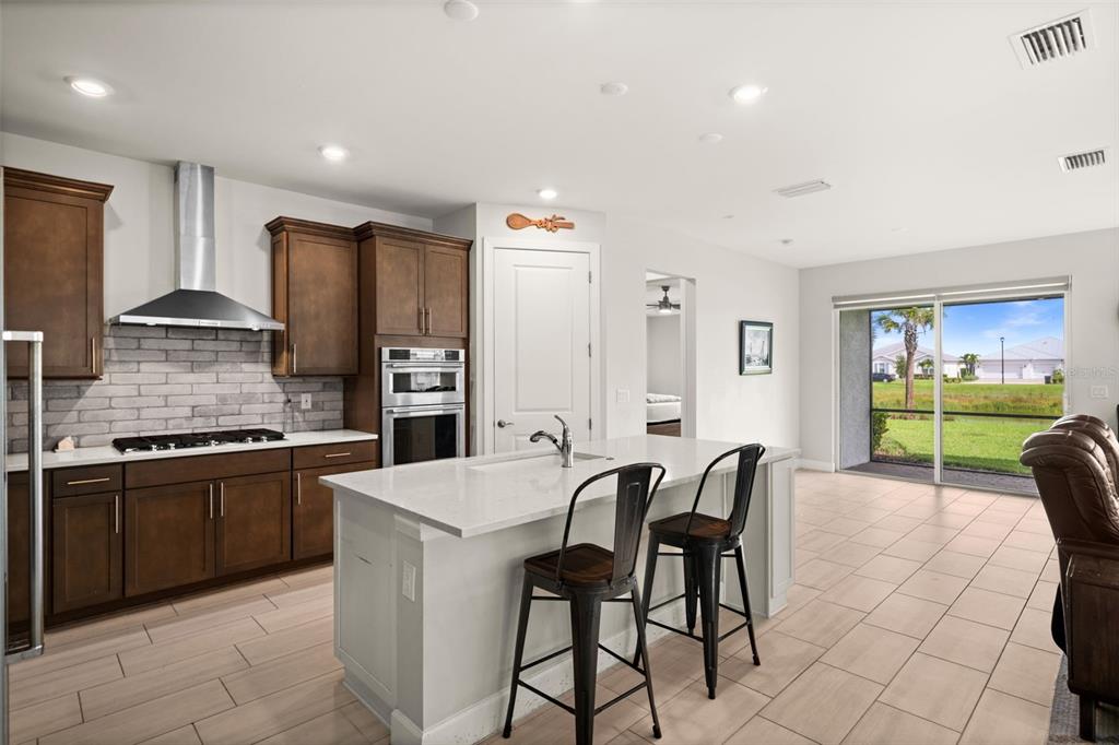 A kitchen with dark wood cabinets, a white island, and a sliding glass door view — 42364 EDGEWATER DRIVE, PUNTA GORDA, FL