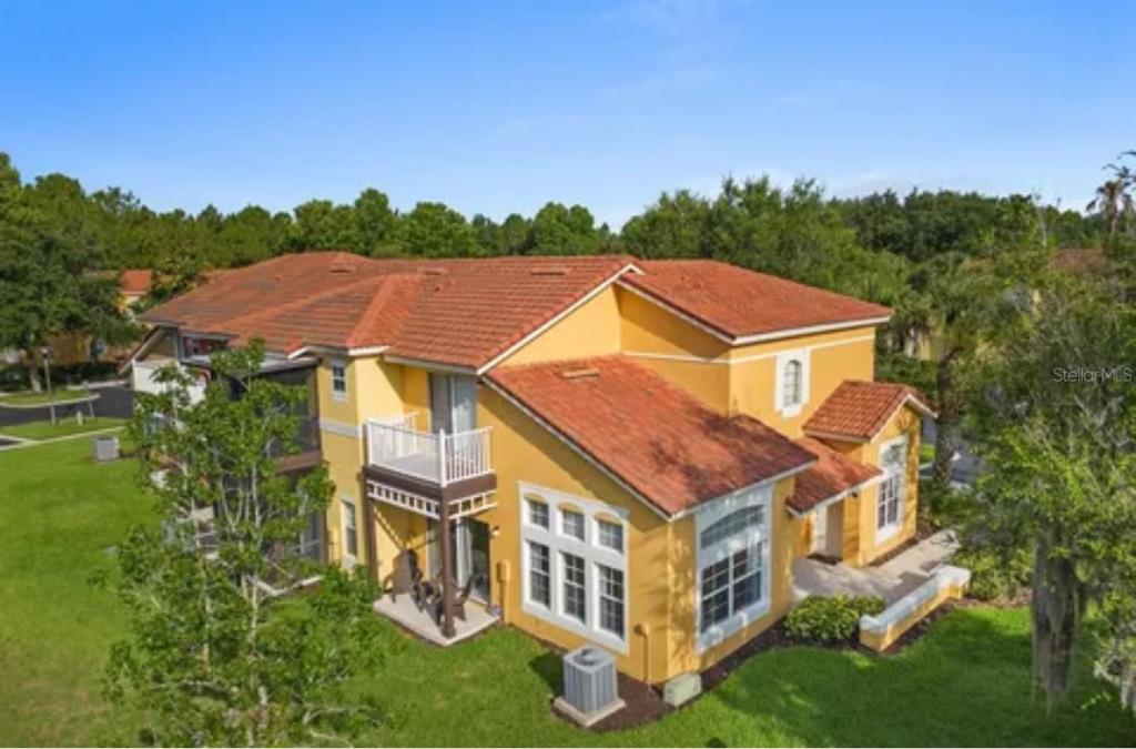 An exterior view of a two-story yellow stucco building with a red tile roof — 8416 BLUE LAGOON DRIVE, KISSIMMEE, FL