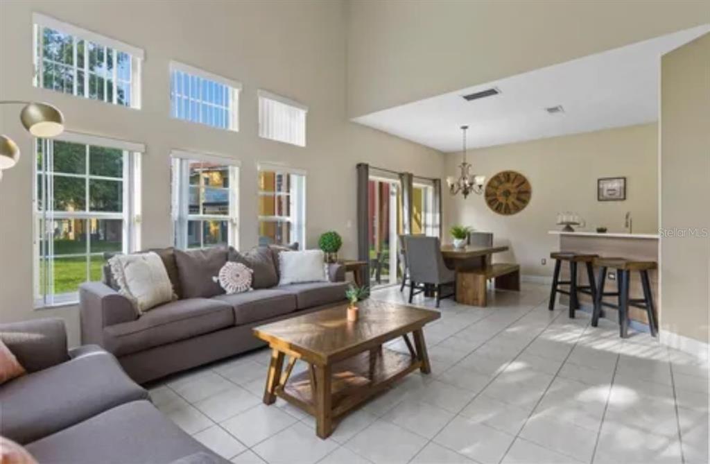 A living room with tile floors, a wooden coffee table, and a dining area nearby — 8416 BLUE LAGOON DRIVE, KISSIMMEE, FL