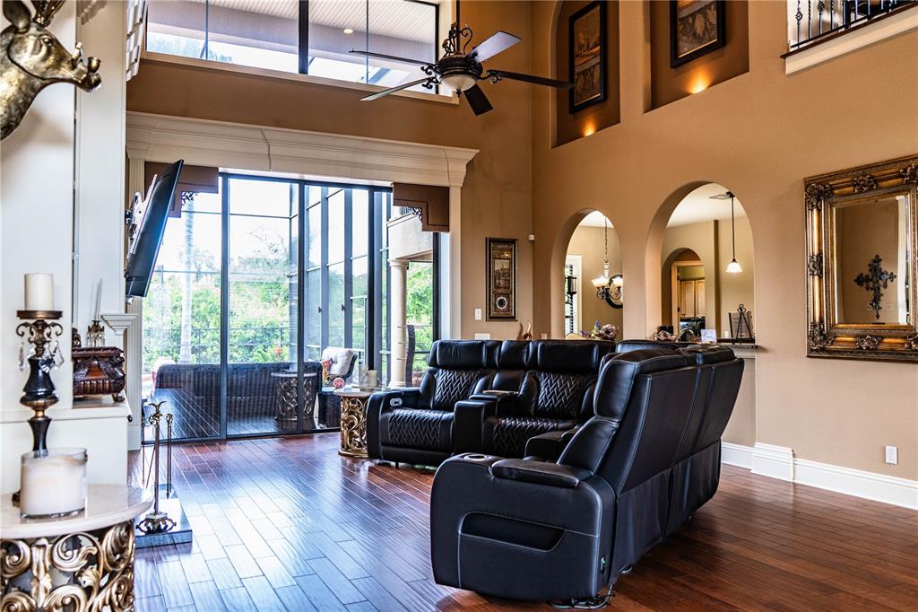 A spacious living room features high ceilings, dark leather recliners, and large glass sliding doors — 6739 EAGLE RIDGE BOULEVARD, LAKELAND, FL