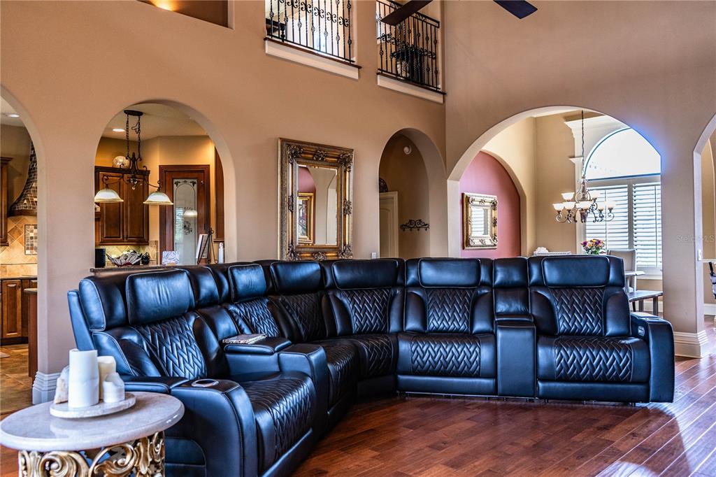 A spacious living room features a large black leather sectional sofa and arched doorways — 6739 EAGLE RIDGE BOULEVARD, LAKELAND, FL