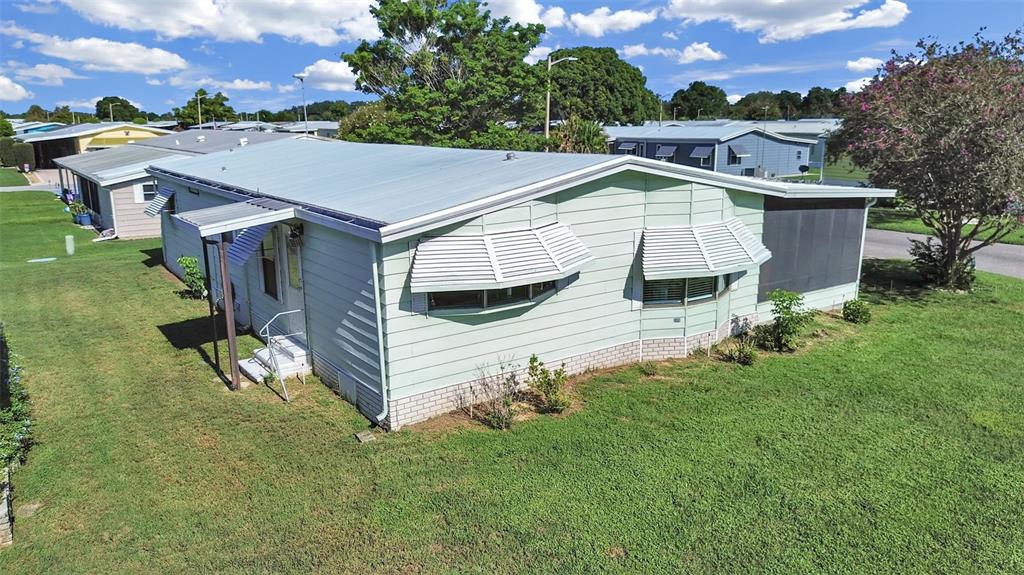 An exterior view of a light green manufactured home with a metal roof and awnings — 4950 FOXWOOD BLVD, LAKELAND, FL
