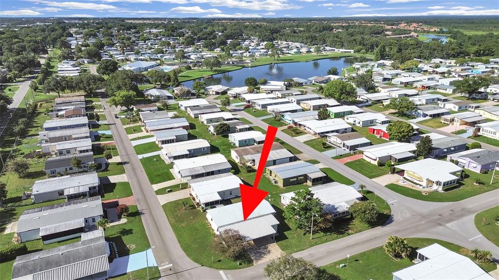 An aerial view shows a manufactured home with a metal carport in a residential community — 4950 FOXWOOD BLVD, LAKELAND, FL