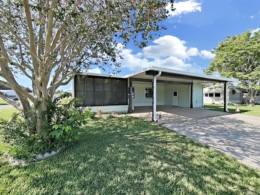 A light green mobile home features a screened-in porch and an attached carport — 4950 FOXWOOD BLVD, LAKELAND, FL
