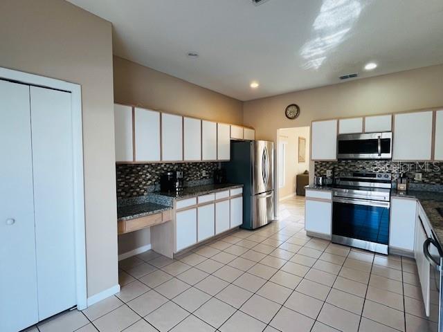 A kitchen features white cabinets, granite countertops, a tile backsplash, and stainless steel appliances — 439 BLOOMINGDALE DRIVE, DAVENPORT, FL