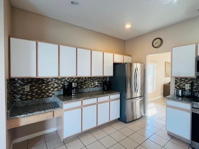 A kitchen features white cabinets, granite countertops, a mosaic tile backsplash, and stainless steel appliances — 439 BLOOMINGDALE DRIVE, DAVENPORT, FL