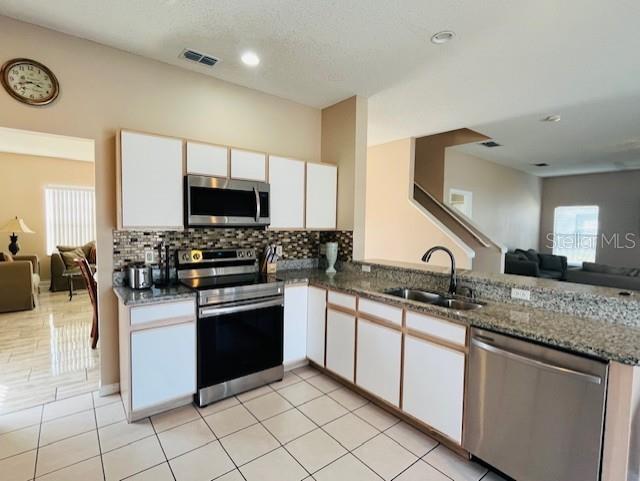 A kitchen features white cabinets, stainless steel appliances, granite countertops, and tiled flooring — 439 BLOOMINGDALE DRIVE, DAVENPORT, FL