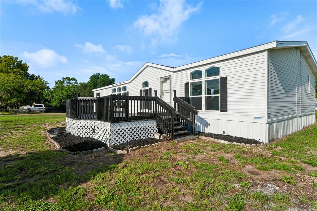 A single-story manufactured home with white siding and a black wooden deck — 4357 ORLANDO AVENUE, BROOKSVILLE, FL