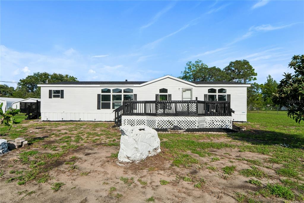 A white manufactured home features a large wooden deck and a prominent white rock — 4357 ORLANDO AVENUE, BROOKSVILLE, FL