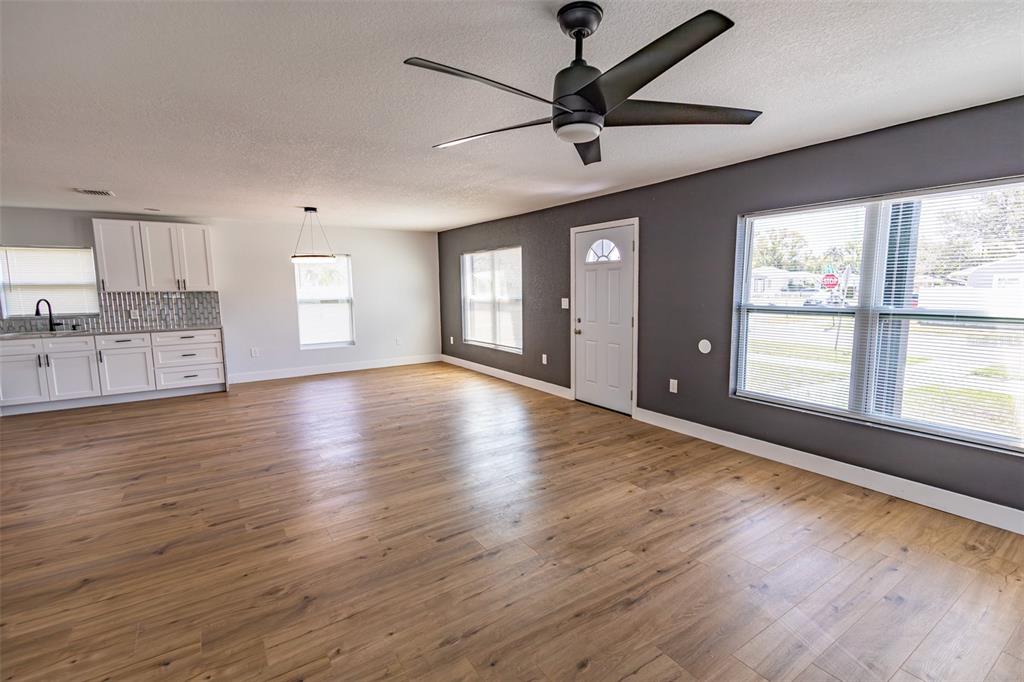 A living room with wood-look flooring, a ceiling fan, and an adjacent white kitchen — 4501 20TH AVENUE S, ST PETERSBURG, FL