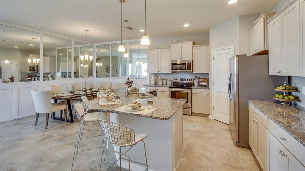 A kitchen with granite countertops, stainless steel appliances, and a dining area with mirrored walls — 4754 NW 39TH STREET ROAD, OCALA, FL