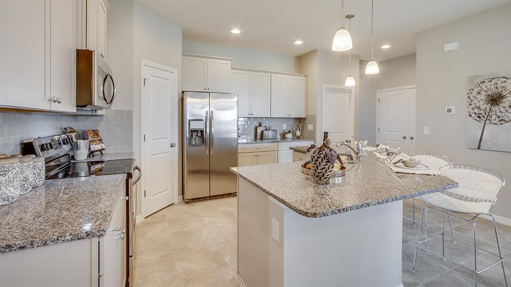 A kitchen features white cabinets, granite countertops, stainless steel appliances, and a central island — 4754 NW 39TH STREET ROAD, OCALA, FL