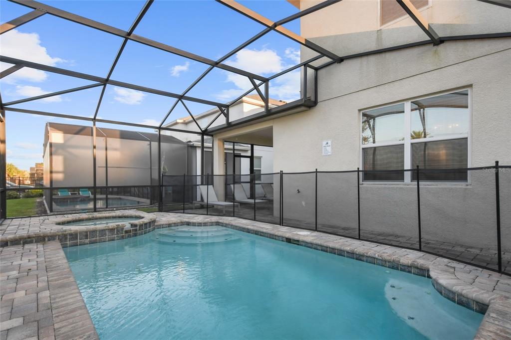 A swimming pool and hot tub are enclosed within a screened lanai behind a house — 8931 AMELIA DOWNS TRAIL, KISSIMMEE, FL