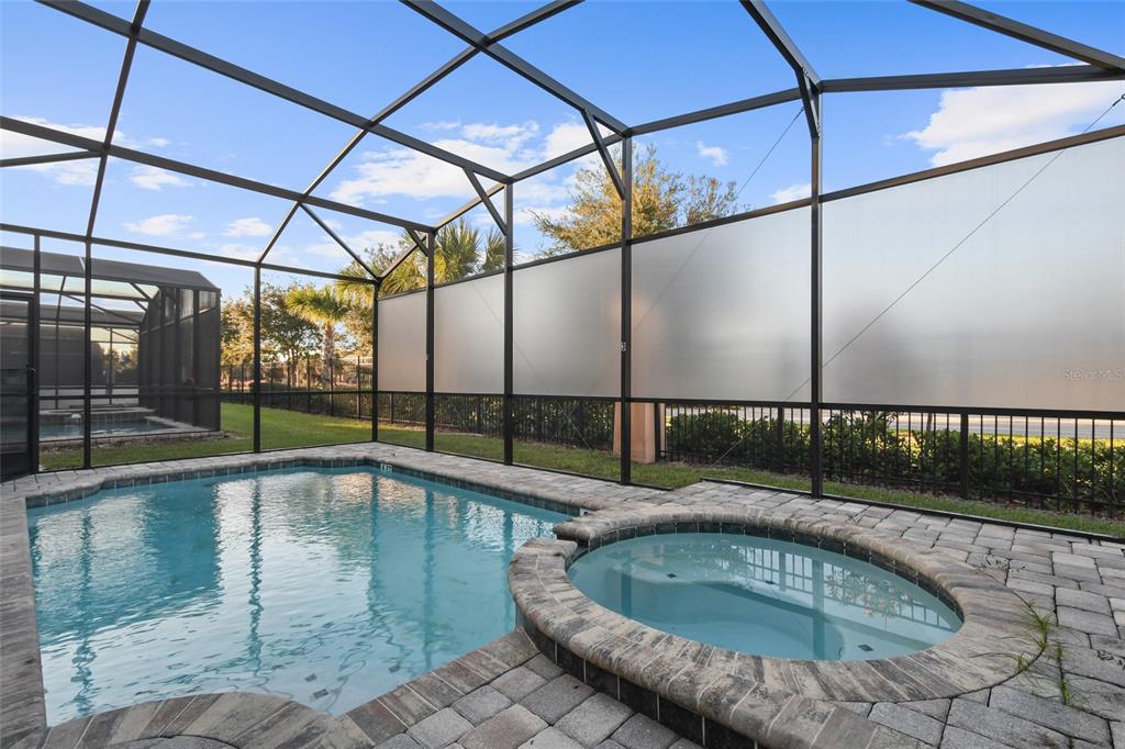 A swimming pool and spa are enclosed within a screened lanai with privacy panels — 8931 AMELIA DOWNS TRAIL, KISSIMMEE, FL