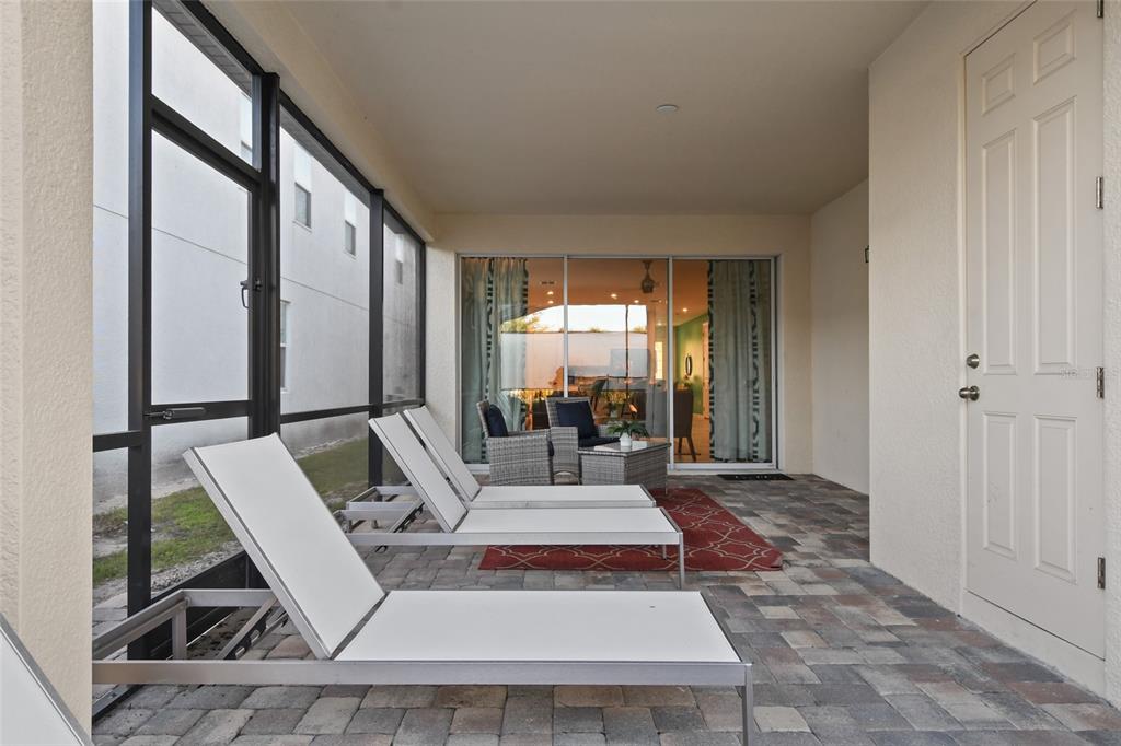 A screened-in patio features two lounge chairs, a small table, and a paved floor — 8931 AMELIA DOWNS TRAIL, KISSIMMEE, FL