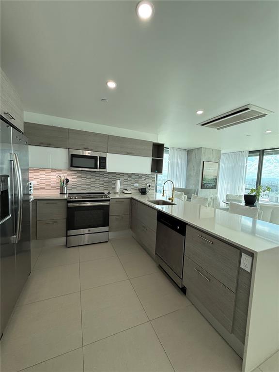A modern kitchen features light wood cabinets, stainless steel appliances, and a white quartz island — 1511 AVE. PONCE DE LEÓN TORRE DEL NORTE 1000 CIUDADELA UNIT 10144, SAN JUAN, PR