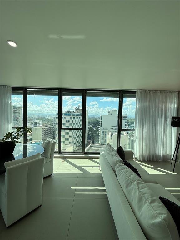 A modern living and dining area with floor-to-ceiling windows overlooking a city skyline — 1511 AVE. PONCE DE LEÓN TORRE DEL NORTE 1000 CIUDADELA UNIT 10144, SAN JUAN, PR