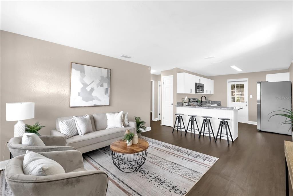 A living room with a sofa and armchairs opens into a kitchen with bar seating — 461 BRENTWOOD DRIVE, DAYTONA BEACH, FL