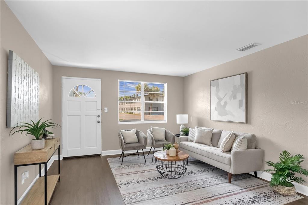 A living room features a white front door, two gray armchairs, a sofa, and wood flooring — 461 BRENTWOOD DRIVE, DAYTONA BEACH, FL