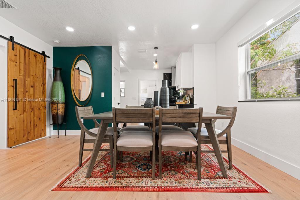 A dining room features a wooden table, chairs, a patterned rug, and a dark green accent wall — 3902 NW 3rd Ave, Miami FL 33127, MIAMI, FL