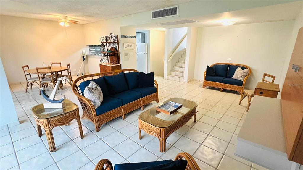 A living and dining area features rattan furniture, blue cushions, and white tile flooring — 1015 HARBOURSIDE DR. UNIT 1015, HUMACAO, PR