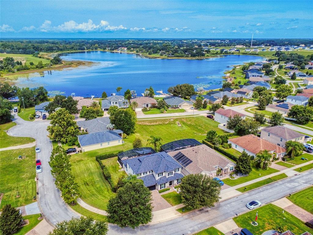 An aerial view shows a suburban neighborhood with houses near a large lake — 9223 IVYWOOD STREET, CLERMONT, FL