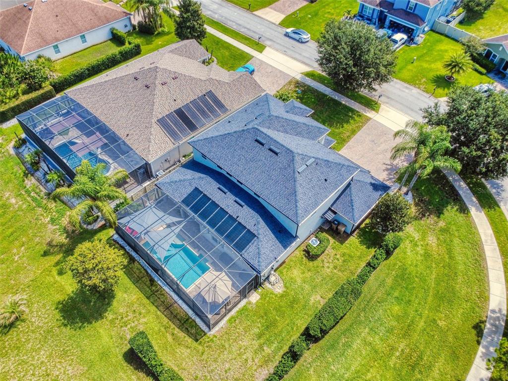 An aerial view shows two adjacent houses with screened-in pools and solar panels on roofs — 9223 IVYWOOD STREET, CLERMONT, FL