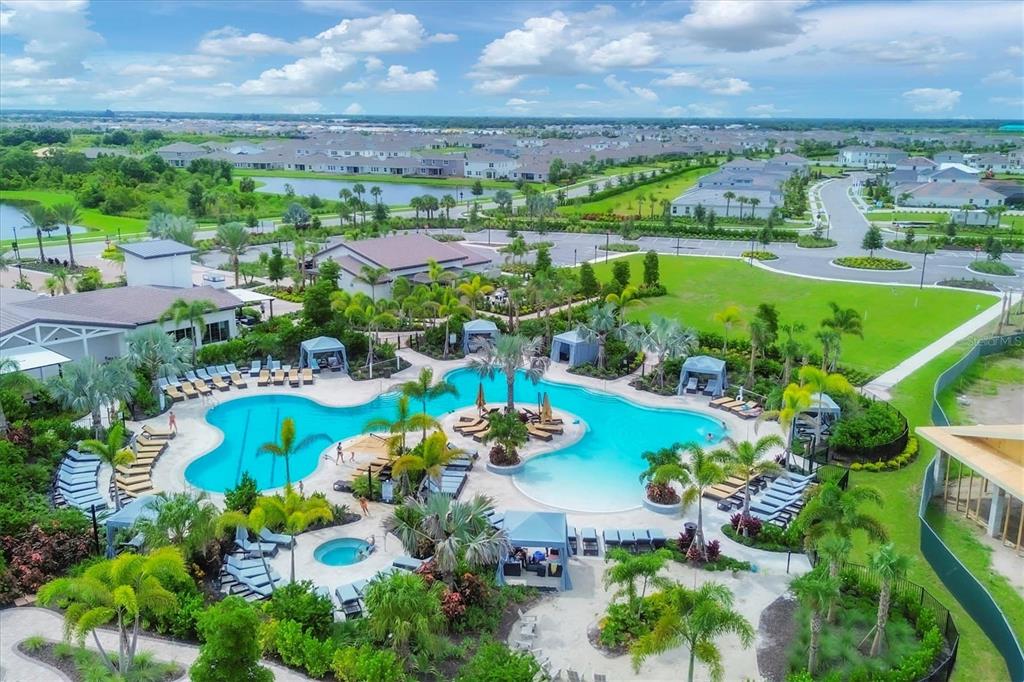 An aerial view of a resort-style swimming pool with cabanas and lounge chairs — 16905 YARD SPRING DRIVE, BRADENTON, FL