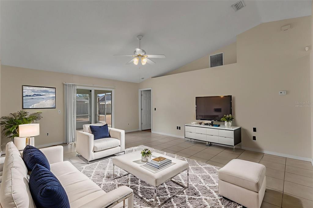 A living room features tile floors, a vaulted ceiling, a ceiling fan, and modern furniture — 36 PINE HILL LANE, PALM COAST, FL