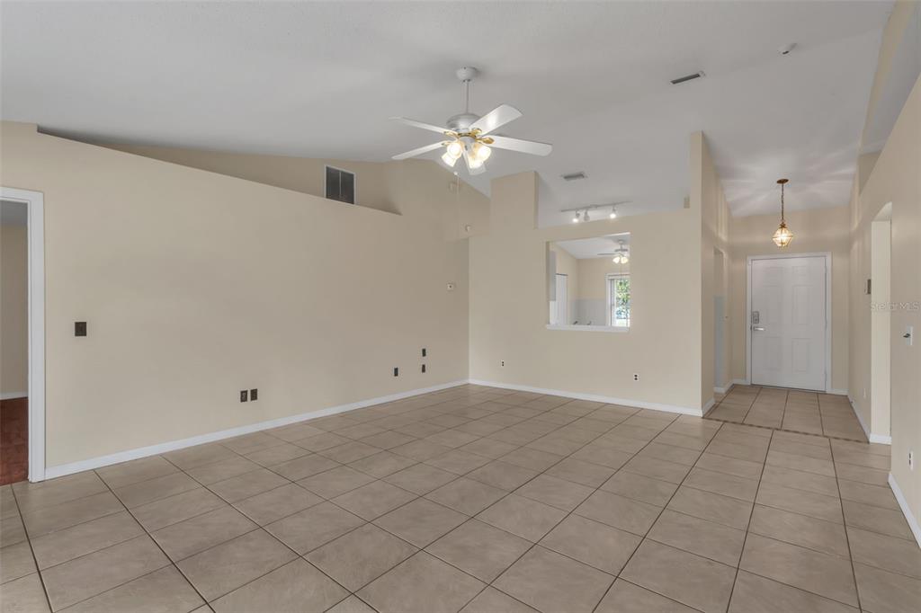 An empty living room features beige tile flooring, a vaulted ceiling, and a ceiling fan — 36 PINE HILL LANE, PALM COAST, FL