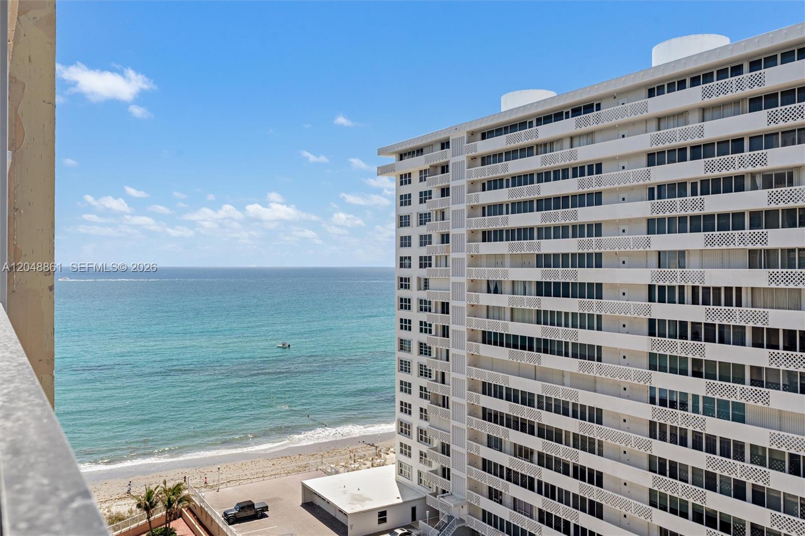 An exterior view shows a tall white apartment building overlooking the ocean and beach — 1180 S Ocean Boulevard # 12F, Boca Raton FL 33432, BOCA RATON, FL
