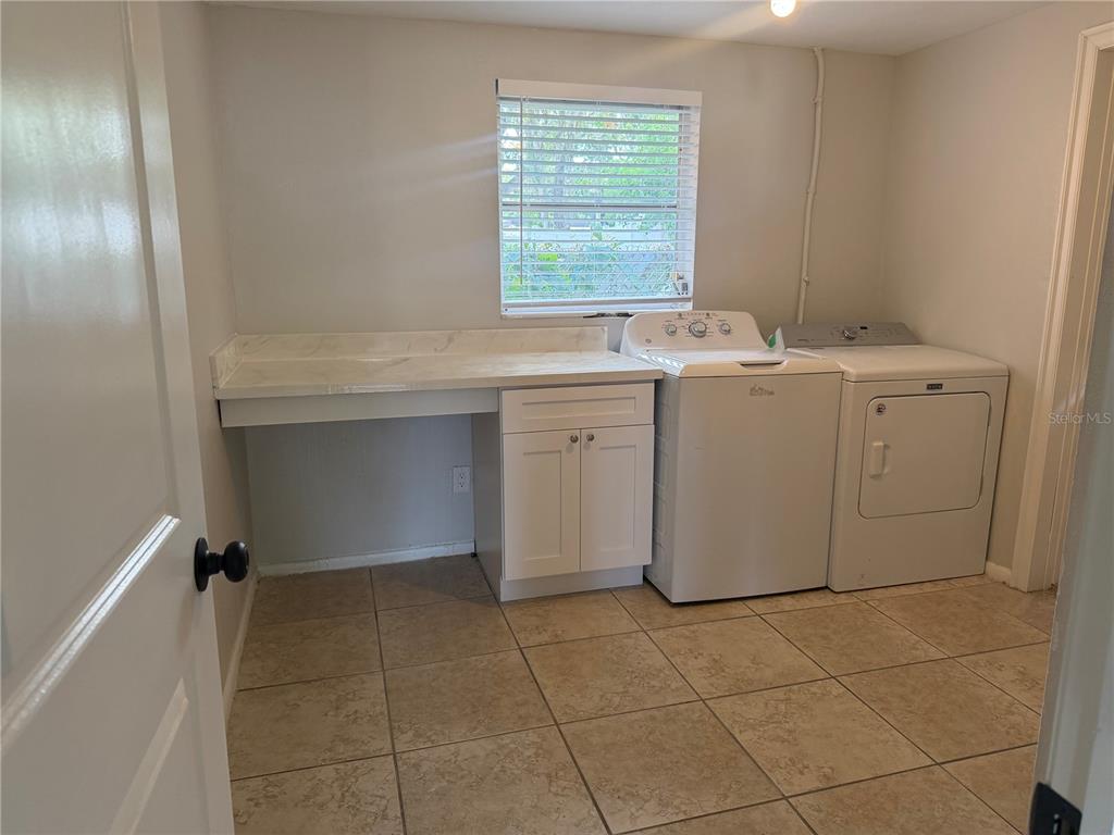 A laundry room with a white countertop, base cabinet, and side-by-side washer and dryer — 3009 W WATERS AVENUE, TAMPA, FL