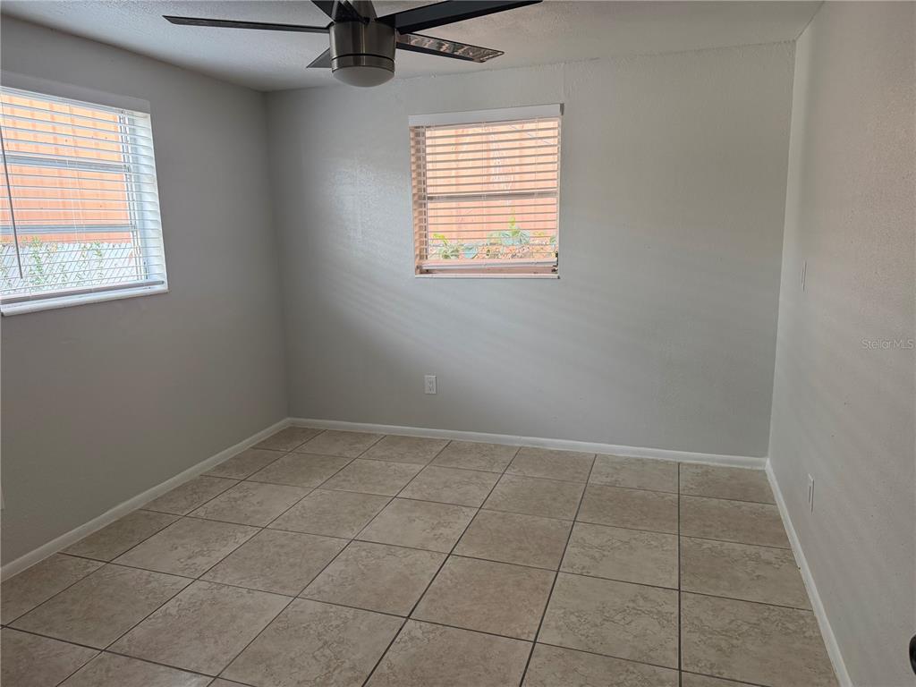 An empty room with light gray walls, tiled flooring, and two windows with blinds — 3009 W WATERS AVENUE, TAMPA, FL