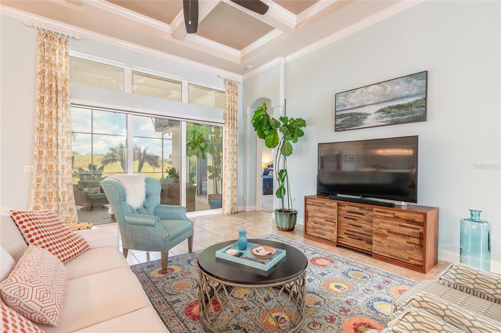 A living room features a patterned rug, a television on a wooden console, and sliding doors — 2909 N ASCIANO COURT, NEW SMYRNA BEACH, FL